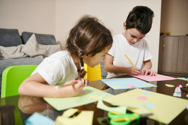 istock Beautiful school boy drawing while her little sister looking at his drawing image during art creativity class 1307977175