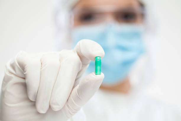 istock Female pharmacist wearing PPE personal protective equipment holding green pill 1307980257