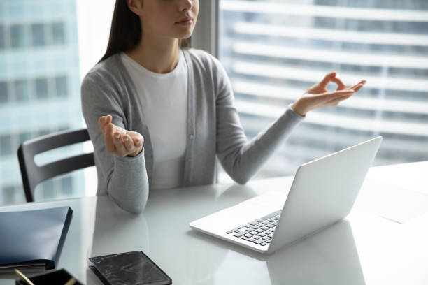 istock Calm young woman employee practicing simple meditation at office table 1307981085