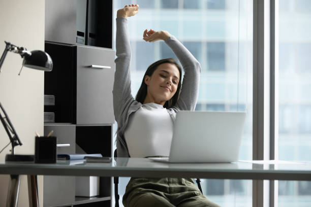 istock Happy millennial female stretching with pleasure sitting at office table 1307981094