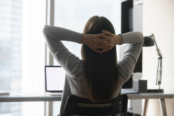 istock Back view of female employee relaxing with hands over head 1307981105