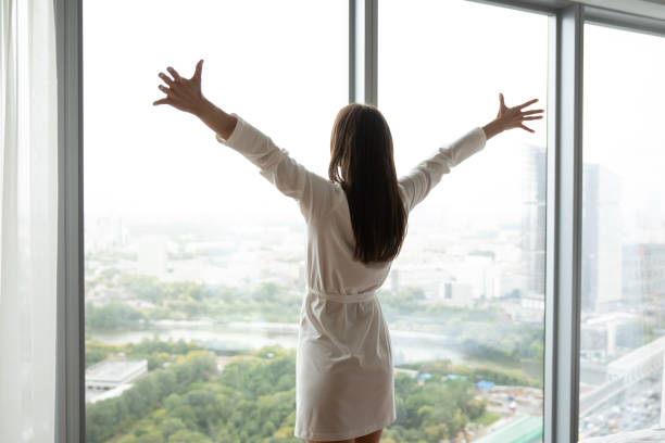 istock Charming woman standing at window wall stretching hands to sides 1307981146