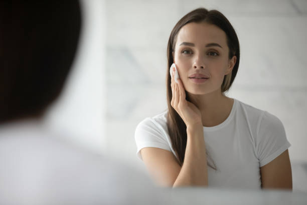 istock Pretty young lady cleansing face with lotion using cotton disc 1307981148