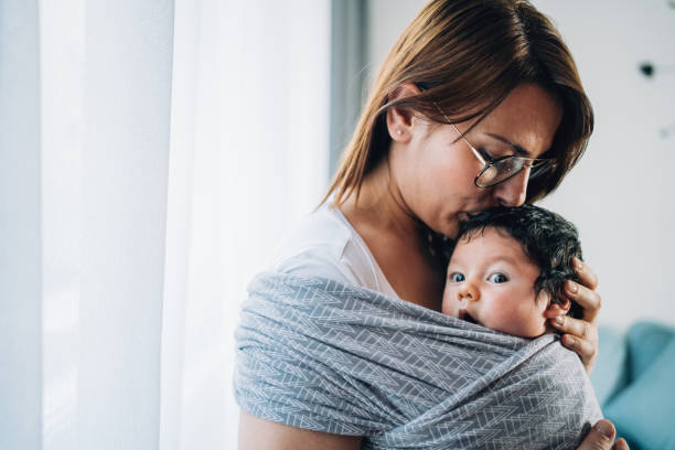 madre che bacia suo figlio in fionda. - shawl foto e immagini stock