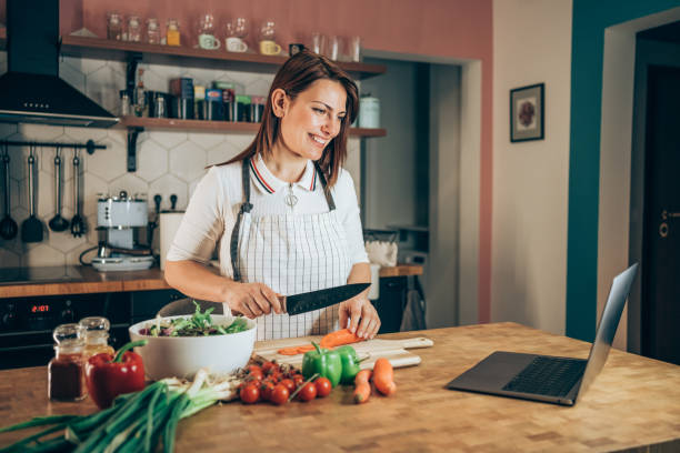 istock Young woman using laptop while cooking healthy meal in the kitchen. 1307988621