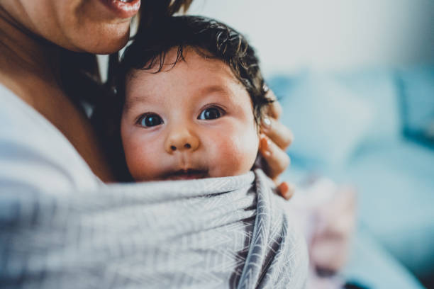 Unrecognizable young mother with her son in sling.