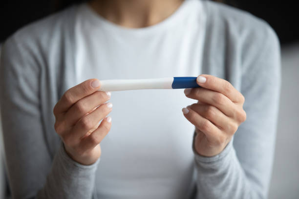 istock Young female holding midstream rapid pregnancy test looking at result 1307989797