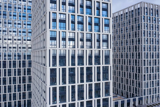 istock Bottom view of office building window close up, reflection and perspective. Modern architecture with sun ray. Glass facade on a bright sunny day with sunbeams on the blue sky. 1307991738