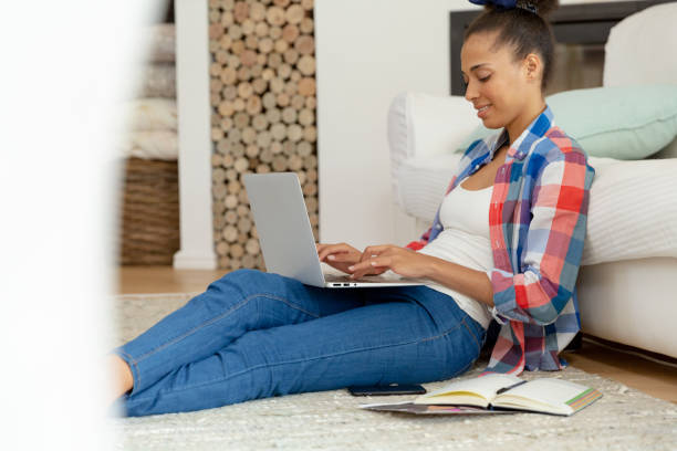 istock Mixed race woman sitting on the floor working from home using laptop 1307991806