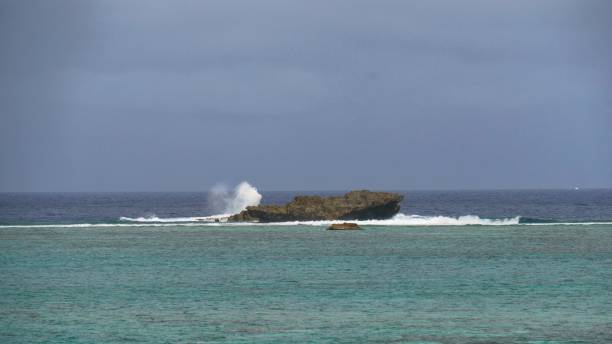 istock Waves crashing against a big rock in a tropical lagoon 1307995018