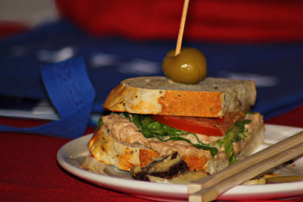 Thick sandwich cut into half and served with an olive on top