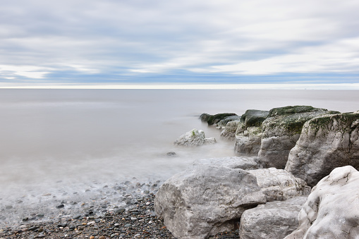 View of rocks on the beach at high tide, shot with long exposure time to create flow
