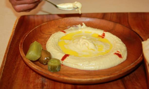 istock Humus dip served in a round wooden plate 1307998449