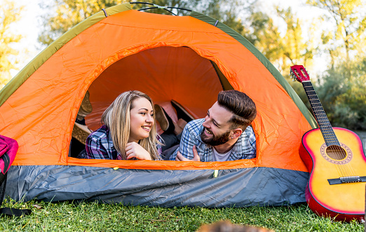 Young happy couple enjoying in the tent during camping day in nature