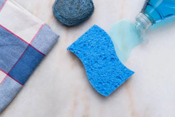 Sponge, dish soap, towel, scouring pad and towel on countertop