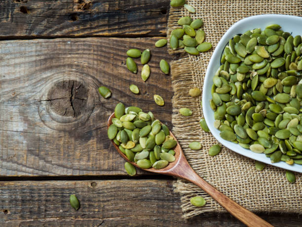 istock Pumpkin seeds in a wooden spoon on an old wooden table . copying text space 1308001663