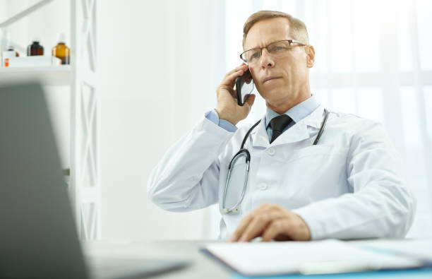 istock Handsome male doctor having phone conversation in clinic 1308004281