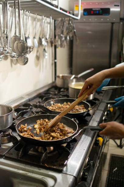Chefs in restaurant kitchen at stove with pan