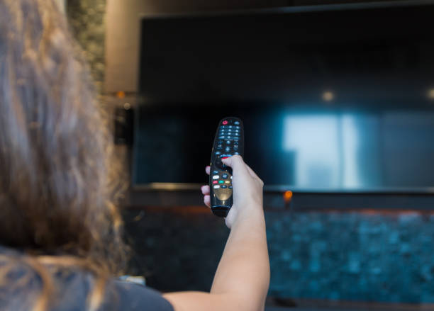 istock Young woman switching TV 1308007189