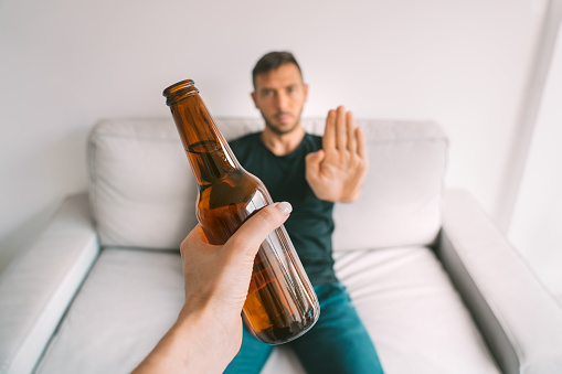 No alcohol. Healthy lifestyle. Young man refuses to drink beer, making stop gesture to bottle of beer