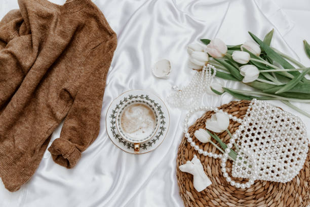 istock White tulip and coffee cup on silk background,  Morning coffee cup spring mood. Luxury romantic background. Top view, flat lay 1308008191