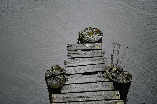 Decaying wooden pier over a river in moody tones