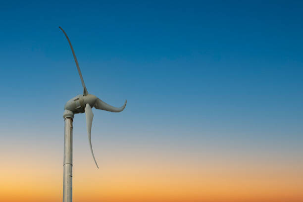 A white wind turbine showing some movement against a deep blue sky.