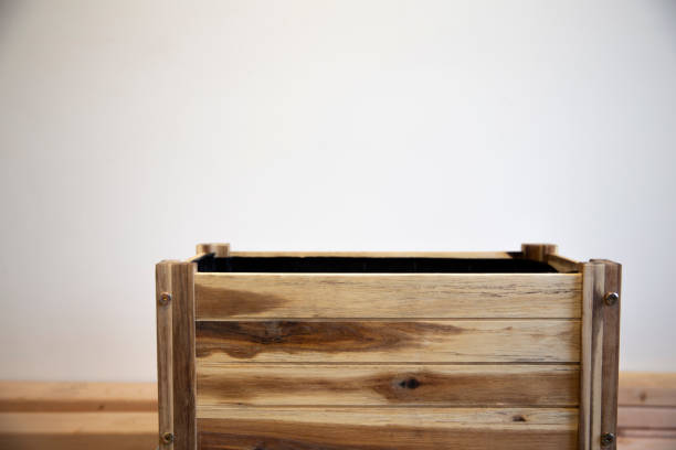 wooden empty rectangular pot for plants on white wall background. Wooden planter, raised bed