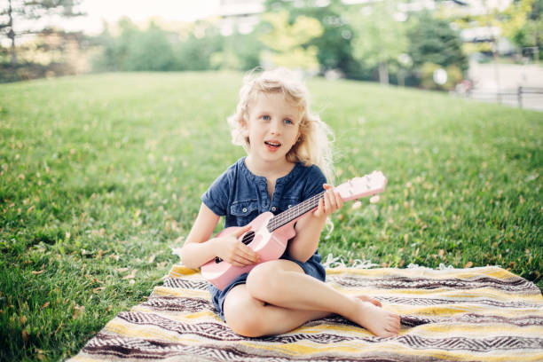 Cute adorable blonde girl playing pink guitar toy outdoors. Child playing music and singing song in park. Hobby activity for children kids. Tender memorable authentic candid childhood moment. Cute adorable blonde girl playing pink guitar toy outdoor. Child playing music and singing song in park. Hobby activity for children kids. Tender memorable authentic candid childhood moment. pink guitar stock pictures, royalty-free photos & images