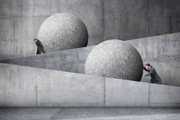 hombre y mujer empujando grandes esferas por una rampa de hormigón - pushing women wall people fotografías e imágenes de stock