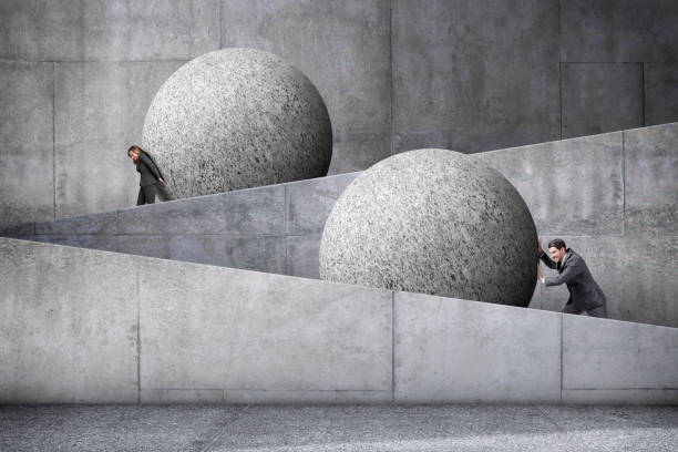 man and woman pushing large spheres up a concrete ramp - pushing women wall people imagens e fotografias de stock