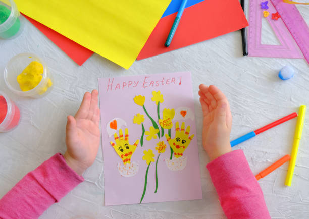 istock Child making card with Easter funny eggs and flowers  from colorful paper. 1308031631