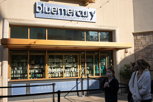 Tigard, OR, USA - Mar 3, 2021: Masked young women walk past the Bluemercury store in Tigard, Oregon, during the coronavirus pandemic. Bluemercury is a chain of American beauty stores based in Washington, D.C..