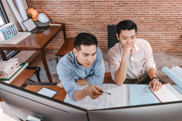 istock engineers and architect reading a building and  drawing outlay construction plan as guide for builders with details on computer. Engineer design and writing blueprint. 1308041881