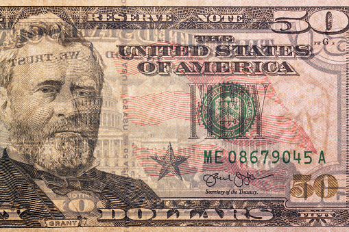 Detail of a 50 US dollar bill with a backlit portrait of President Willis Grant with visible backsplash and watermarks