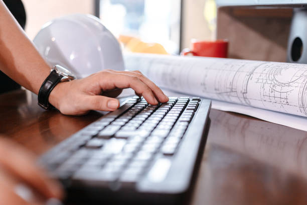 istock Architecture typing on keyboard for working and safty helmet, planing design on the table. 1308042792