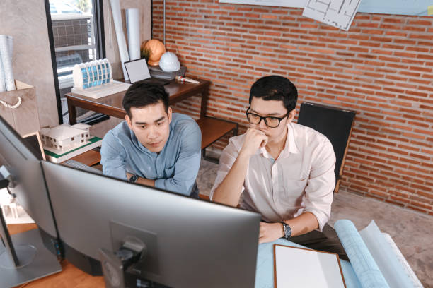istock engineers and architect reading a building and  drawing outlay construction plan as guide for builders with details on computer. Engineer design and writing blueprint. 1308042913