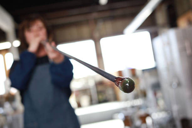 A woman making a glass container blown glass