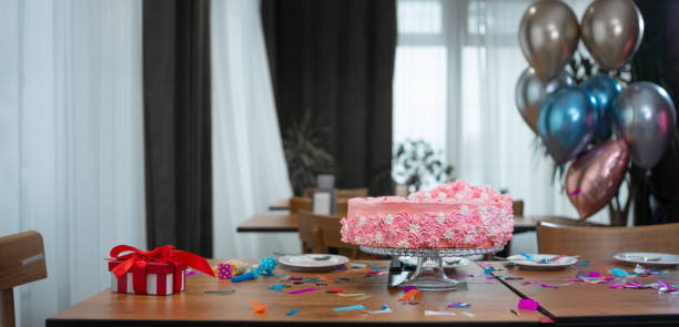 istock a pink birthday cake stands on the table, a red box with a bow and balloons. 1308048452