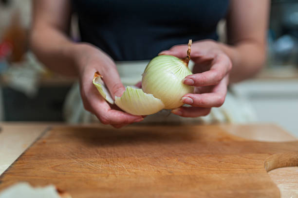 istock A Woman is Peeling a Fresh Onion in the Kitchen. 1308056677