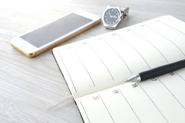 Business schedule book and smart phone on desk with nobody