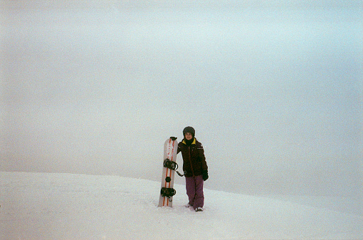 Woman snowboarding in mountains. Camera film