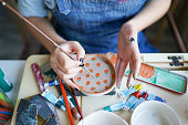 istock unrecognizable woman's hand paints ceramics 1308062234