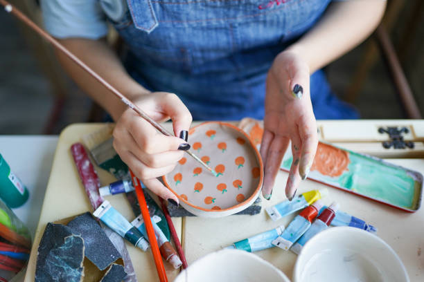unrecognizable woman's hand paints ceramics stock photo