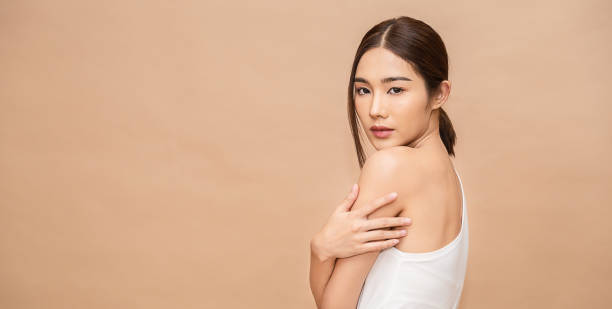 portrait of beauty  smiling face asian woman applying a lotion to her arm skin high fashion casual cloth. cute asian girl. skincare body lotion, beauty clinic skincare spa indoors woman lifestyle banner - moisturizer women cosmetics body imagens e fotografias de stock