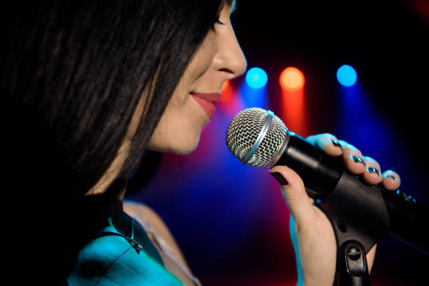 istock Singer with microphone on the colorful light stage background 1308066371