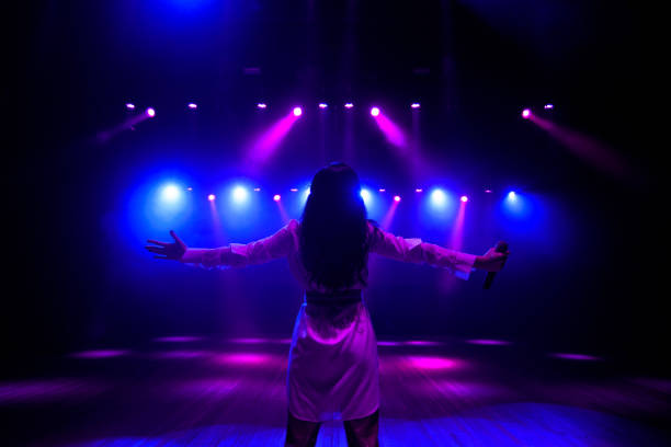 istock Unrecognizable singer standing on stage at microphone, back view, neon lights 1308066446
