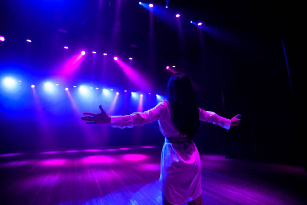 istock Unrecognizable singer standing on stage at microphone, back view, neon lights 1308066452