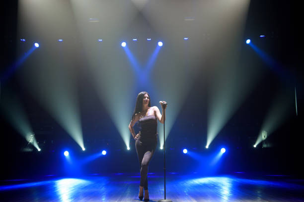 istock Pop musician with microphone singing a song on the stage in blue light background. 1308066504