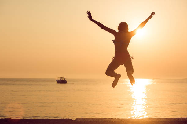 istock Child is jumping into the sea from a pier at sunset 1308069088